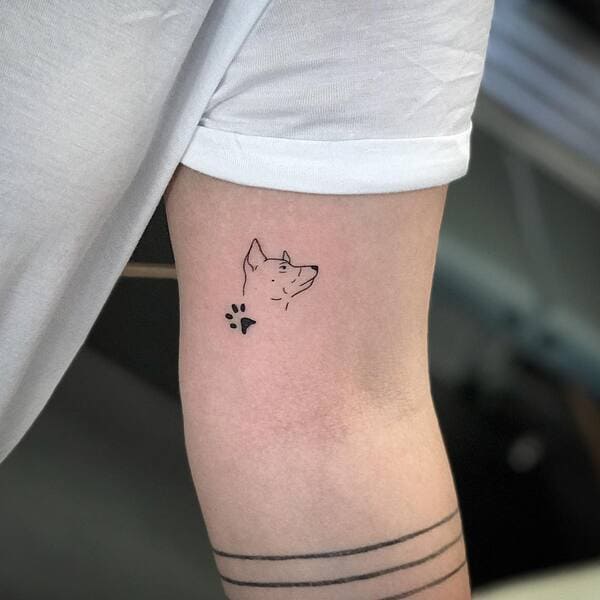 62 Beautiful Remembrance Tattoos for Dogs: A Heartfelt Tribute 19 Minimalist dog profile and paw print memorial tattoo with line details on forearm