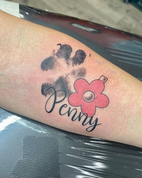 62 Beautiful Remembrance Tattoos for Dogs: A Heartfelt Tribute 39 Dog paw print memorial tattoo with name Penny and pink flower design