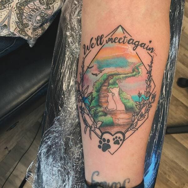 62 Beautiful Remembrance Tattoos for Dogs: A Heartfelt Tribute 54 Rainbow bridge memorial tattoo with cat and dog silhouettes on path, text 'We'll meet again