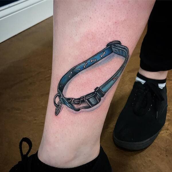 62 Beautiful Remembrance Tattoos for Dogs: A Heartfelt Tribute 8 Dog collar memorial tattoo with bone pattern and buckle design on ankle, realistic shading in blue and grey tones