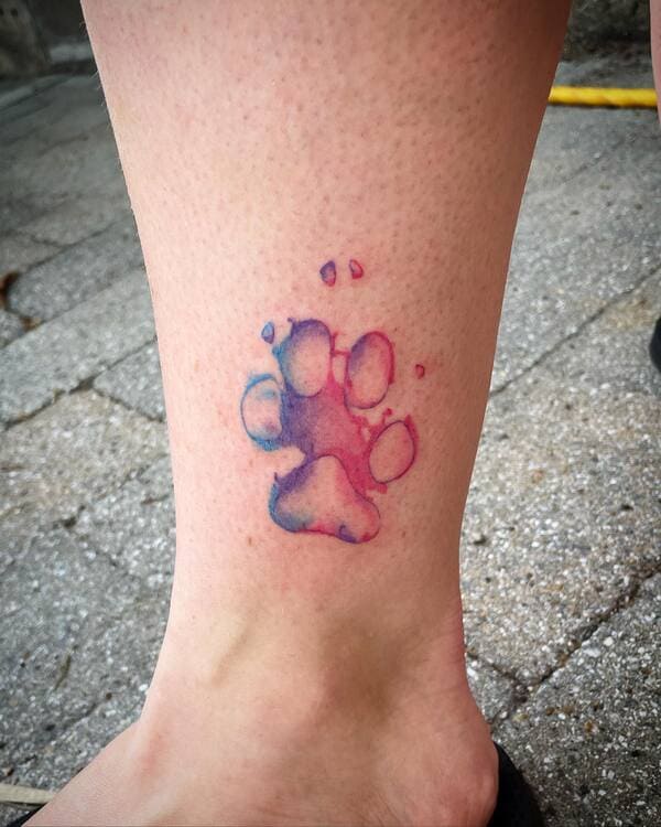 62 Beautiful Remembrance Tattoos for Dogs: A Heartfelt Tribute 40 Watercolor style dog paw print in purple and pink ombre on ankle