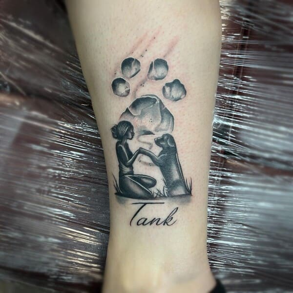 62 Beautiful Remembrance Tattoos for Dogs: A Heartfelt Tribute 13 Custom dog remembrance tattoo with paw print and silhouette of girl with dog named Tank, black and grey shading